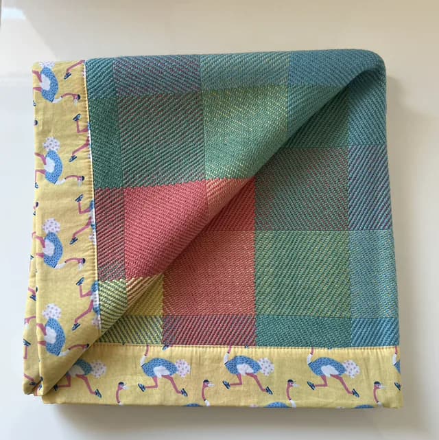 Plaid bébé plié à carreaux tissés colorés et bordure jaune à motif d'oiseaux.