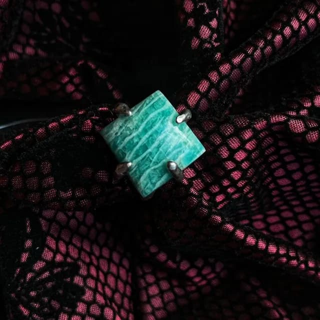 Bague ornée d'une amazonite carrée aux nuances turquoise, sertie de griffes en argent sur tissu noir.