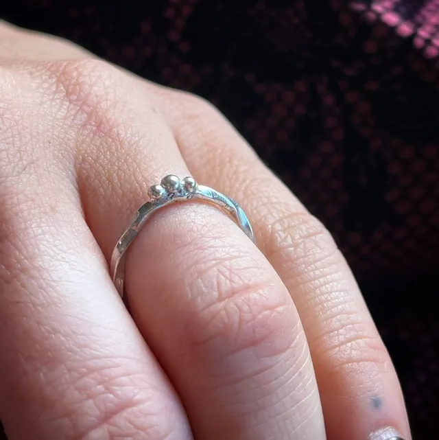 Bague fine en argent avec trois petites perles portée au doigt