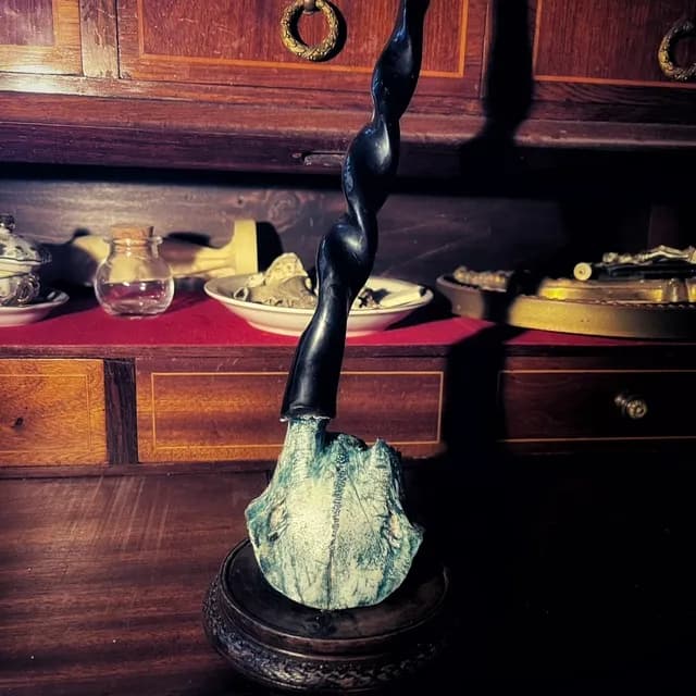Bougeoir rituel avec bougie noire torsadée sur socle en bois verni et pièce sculptée aux reflets vert d'eau.